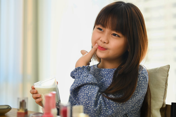 亚洲可爱小女孩拿着一杯牛奶的照片，录制视频分享到社交媒体上。图片下载