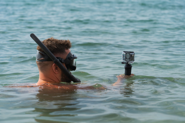 一名男子带着运动相机在海中潜水，特写照片。图片下载