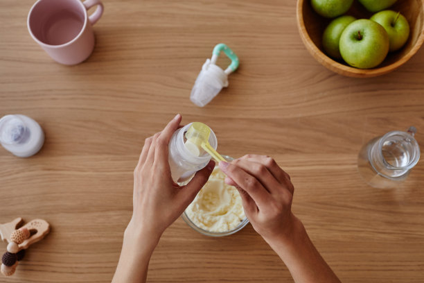 在厨房餐桌上制作婴儿配方奶粉的妇女图片下载