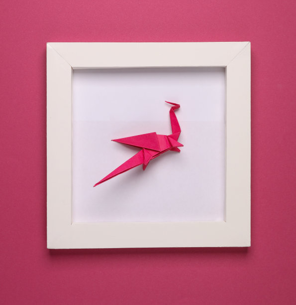 折纸龙在白色的方形框架，粉红色的背景。美学最小的静物。概念上的照片。俯视图图片下载