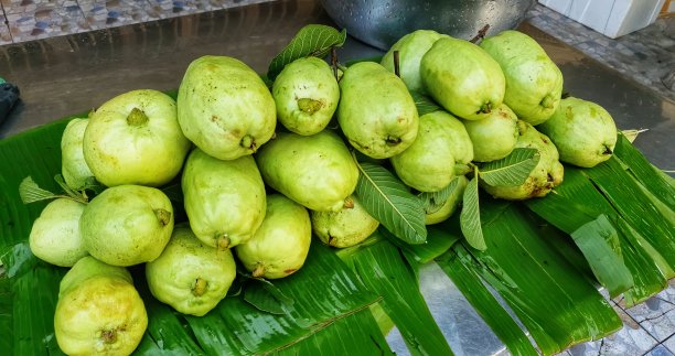 芭蕉叶上有一堆绿色的水果。美丽的绿色番石榴图片。图片下载
