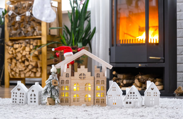 钥匙放在圣诞树上，小房子在舒适的家里，靠近燃烧的火炉壁炉的圣诞装饰。新年礼物。保险，搬家，抵押贷款，租金和房地产图片下载