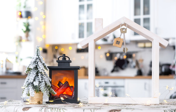 钥匙和小房子的小尺寸舒适的家与圣诞装饰的餐桌上喜庆的白色厨房。新年礼物。保险，搬家，抵押，租赁和购买房产图片下载