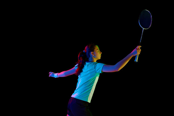 精力充沛的肖像锦标赛准备，以熟练的羽毛球运动员展示她的动作在霓虹灯的黑色背景。图片下载