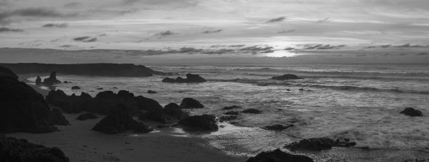 沙滩上美丽日出的灰度照片。图片下载