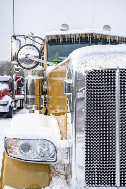 部分金天驾驶室大钻机半卡车拖拉机覆盖着冰雪和镀铬格栅站在卡车站冬季停车场旁边的另一辆半卡车图片下载