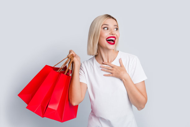 照片中，穿着白色t恤的漂亮女人拿着购物袋盯着白色背景上的空地图片下载