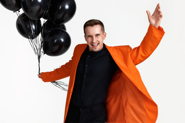 穿着橙色夹克，带着黑色气球的帅哥图片下载