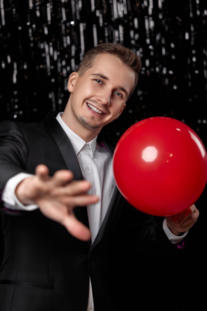 穿黑色夹克的白种人拿着红色气球图片下载