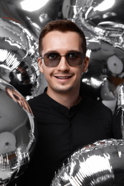 戴着墨镜的男人，手里拿着很多银色的气球图片下载