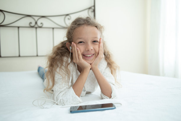 孩子戴着耳机在卧室听音乐。高质量照片图片下载