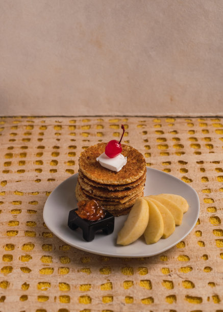 细节的照片。美味的素食热蛋糕，配上一片椰子黄油、糖浆樱桃和桃子果酱，配上几片黄苹果。装在白色盘子里图片下载