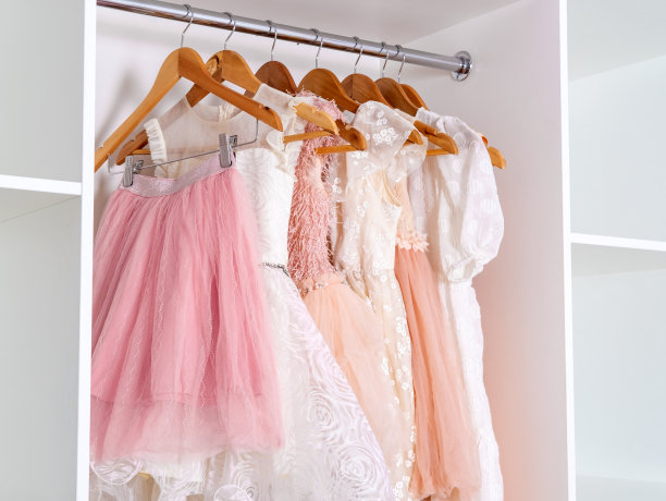 各式各样的儿童连衣裙和裙摆挂在白色的衣橱里，裙摆由华丽的欧根纱制成。图片下载