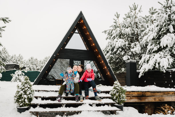 寒假在户外。母亲、父亲、女儿、儿子在乡间别墅度假。妈妈、爸爸带着孩子庆祝新年。带着孩子的家庭在雪林的山地乡村别墅的露台上玩耍图片下载