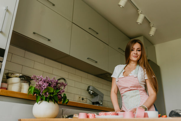 友善微笑的女性专业糖果师用糕点袋给纸杯蛋糕浇上奶油的照片。看着镜头。在室内的形象。做奶油蛋糕的女糕点师图片下载