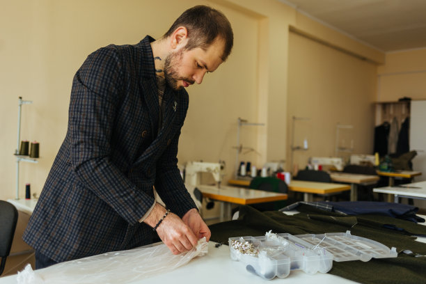 裁缝裁剪毛织品。线条图案。匠人用毛织品制作领结用的矩形坯料。在纺织车间使用缝纫机。图片下载