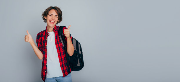 一张年轻、兴奋、迷人的女学生的横幅照片，她有着时髦的发型和背包，微笑着竖起大拇指。大学，学习，学校，教育，学院，上课，学习知识。图片下载