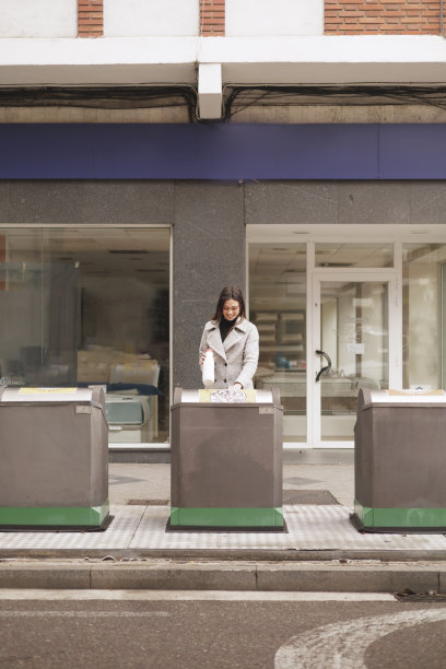 年轻女子在城市户外回收垃圾的正面照片。真实的人。图片下载