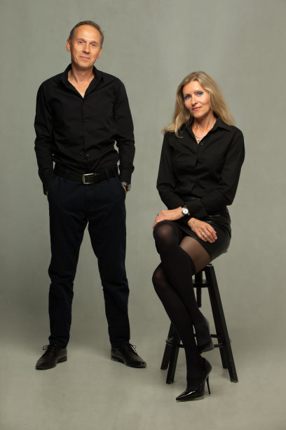 一对成熟夫妇的肖像。一对夫妇，两个朋友一个灰白头发的老人和一个穿黑衣服的金发女人摆姿势，单独在灰色背景下，工作室的肖像图片下载