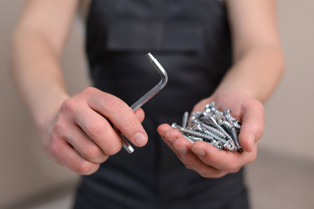 家具装配工手里拿着沉头螺钉和六角扳手(特写)。施工理念，勤杂工图片下载