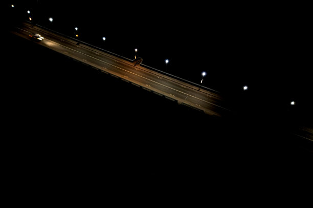 汽车经过的夜桥。灯光模糊地照亮了河上的轮廓。无人机的交通状况，警方监控，交通专家，追逐偷车贼图片下载