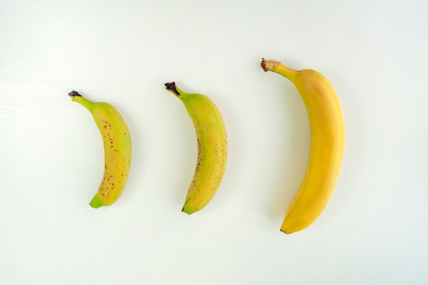 不同种类的香蕉。白色桌子背景上不同大小的黄色香蕉。图片下载