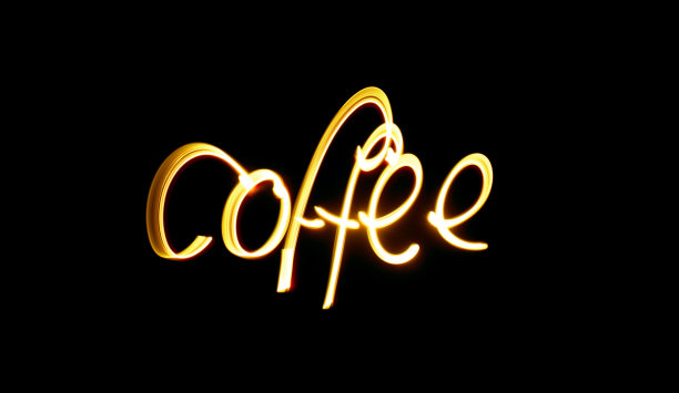 在一张黑色背景的长时间曝光照片中，“咖啡”一词在鲜艳的橙棕色灯光下书写。光绘摄影图片下载