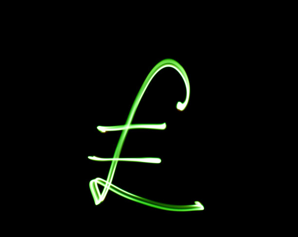 一张在黑色背景下的长曝光照片中，在充满活力的绿光下的英镑货币符号的照片。光绘摄影图片下载