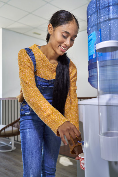 漂亮的哥伦比亚拉丁女孩在共用工作中心喝着机器里的水休息图片下载