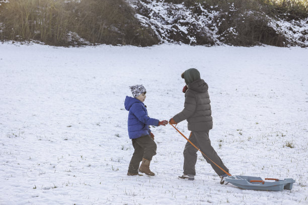 两个不同年龄的兄弟在一个晴朗的雪天里滑雪。图片下载