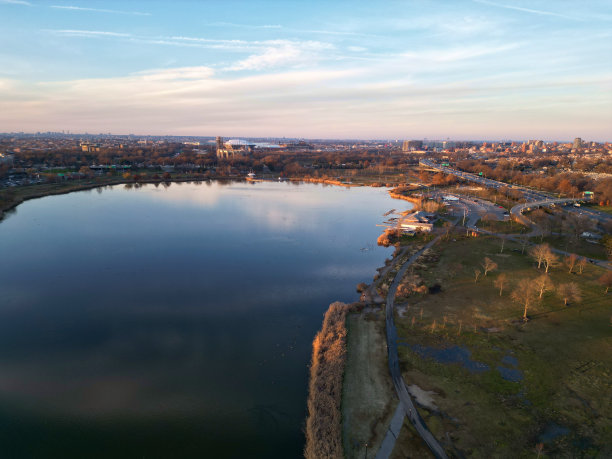 亚瑟阿什体育场(网球馆在科罗纳法拉盛草地，皇后区)的鸟瞰图与草地湖水在前景(无人机照片从上面)旁边的世界博览会场地纽约，纽约市图片下载