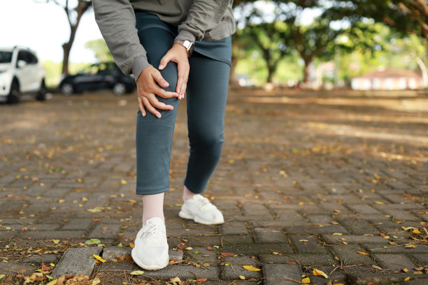 关节疼痛、关节炎和肌腱问题。一个亚洲穆斯林妇女在公园里摸着膝盖的痛点。特写照片图片下载
