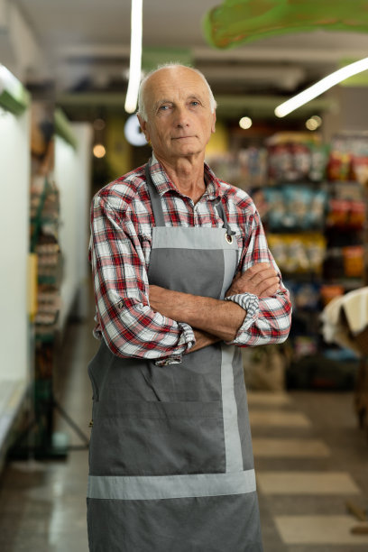 一个老超市工作人员站在乳品部看着镜头的肖像图片下载