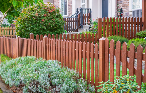 房子周围有漂亮的木栅栏。木栅栏和绿色草坪。入口门。街头的照片图片下载