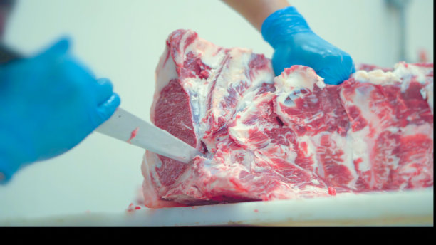 肉类行业，屠夫在屠宰场的餐桌上用刀切生肉。图片下载
