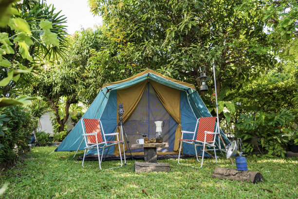 古色古香的小木屋帐篷，古色古香的油灯，复古的椅子，一组露营帐篷，在森林里的森林露营区，在木桌上有户外咖啡制作设施。图片下载