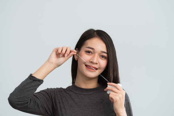 亚洲妇女用牙线做牙套。牙齿矫正器戴在女性洁白的牙齿上，使牙齿均匀。托架系统在微笑的嘴，近距离照片牙齿，微距拍摄，牙医的健康理念。图片下载