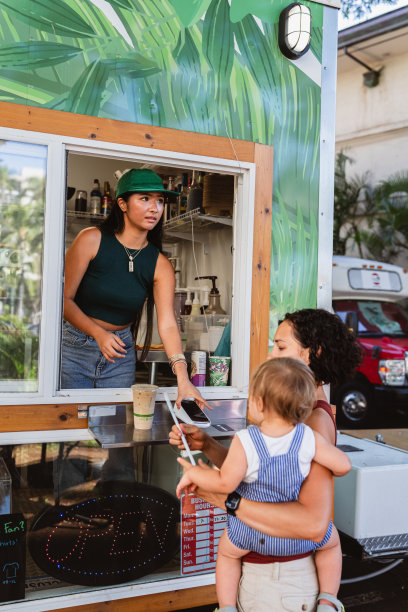 一名妇女抱着儿子在户外咖啡馆买咖啡图片下载