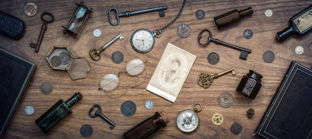 一堆古玩摊在桌子上。旧硬币、眼镜、照片、玻璃瓶、钥匙、手表和指南针。古董收藏。图片下载