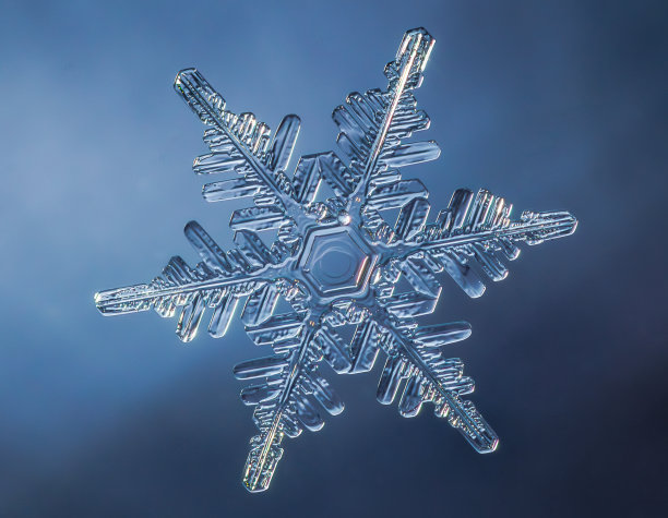 雪花在光滑的渐变背景。玻璃表面真实雪晶的微距照片。这是一朵花纹不寻常的小雪花。图片下载