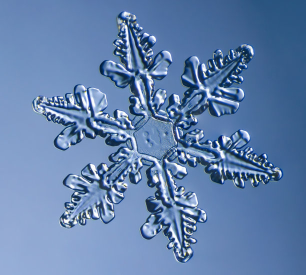 雪花在光滑的渐变背景。玻璃表面真实雪晶的微距照片。这是一朵花纹不寻常的小雪花。图片下载