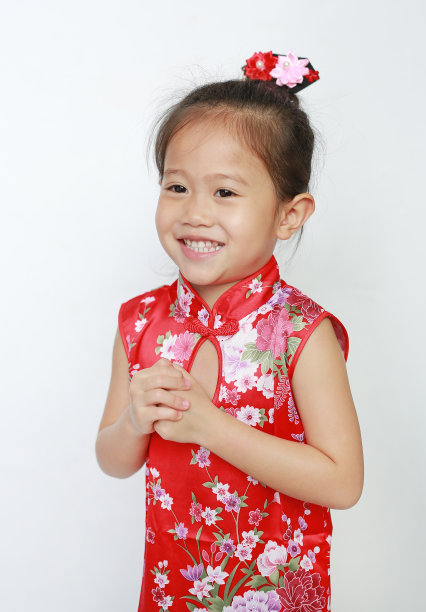 微笑的亚洲小女孩穿着红色旗袍，在白色的背景上有中国新年的问候手势。图片下载