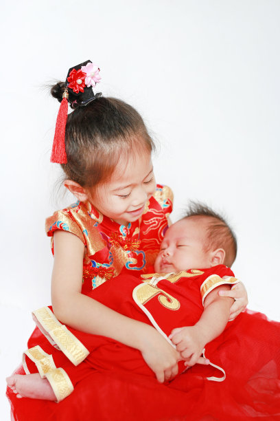 可爱的亚洲小女孩和穿着旗袍的小男孩在传统的中国新年期间被隔离在白色的背景上。图片下载