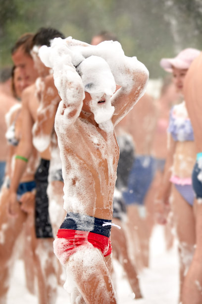 快乐的小男孩，头上有泡沫，在水上公园玩得很开心，在一个阳光明媚的炎热的夏天，穿着湿泳衣参加泡沫派对或度假图片下载