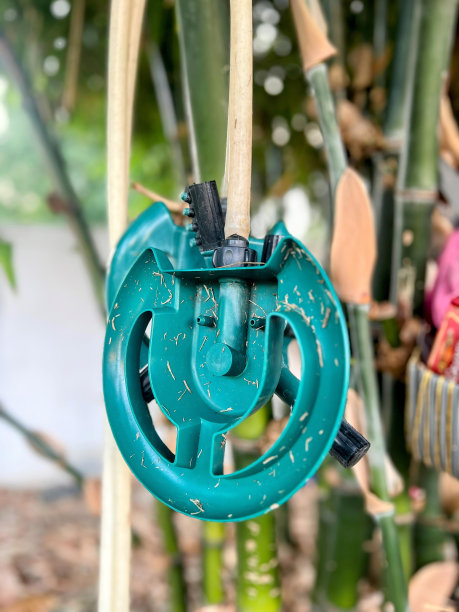 一张挂在竹子上的绿色洒水器的照片。图片下载