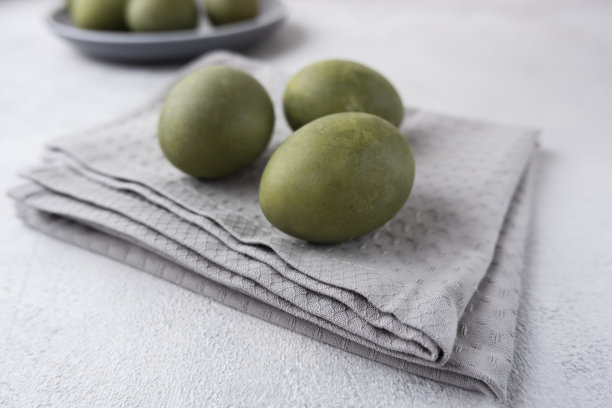 绿色的鸡蛋放在浅色背景的灰色毛巾上。最小的概念。从上面看。复活节彩蛋。准备复活节的照片。图片下载