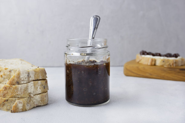 浅灰色背景的玻璃罐里装着草莓酱，配上切片面包。配上美味的自制果酱。早餐和零食的概念。图片下载