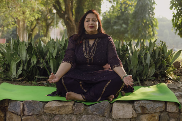 美女在绿油油的公园里做瑜伽。瑜伽姿势。冥想的女人。精神和健康。各种各样的印度姿势。图片下载