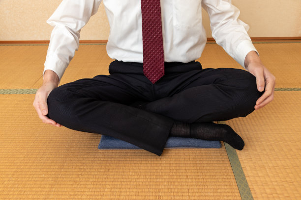 一个男人脱下夹克，盘腿坐在垫子上图片下载