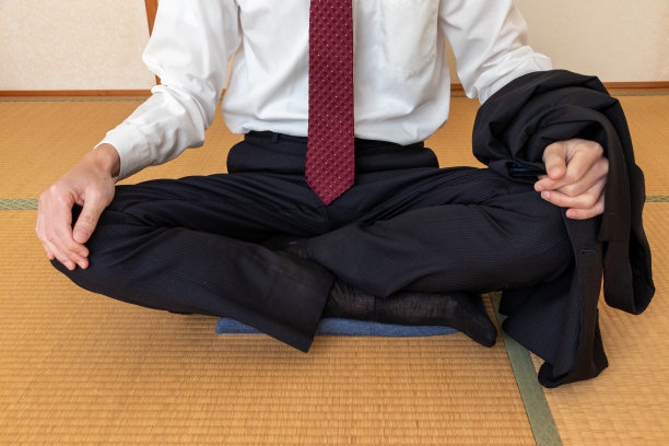 一个男人脱下夹克，盘腿坐在垫子上图片下载